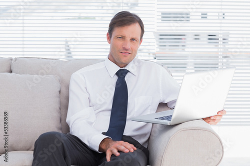 Businessman sitting on couch looking at camera