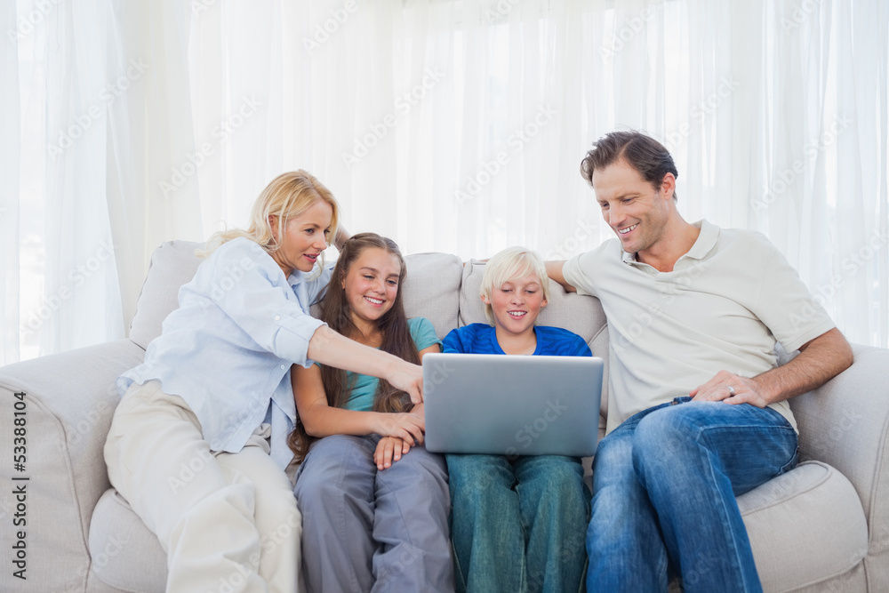 Family sitting on a couch while using a laptop Family sitting on a couch while using a laptop