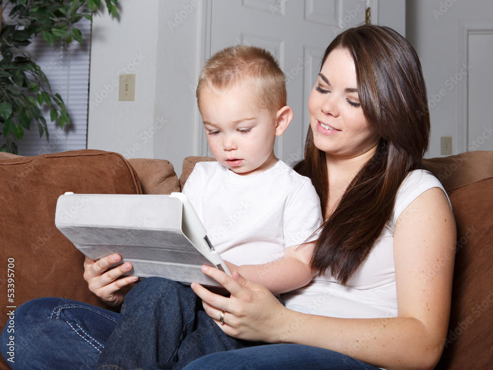 Smiling woman and her son reading on tablet together Smiling woman and her son reading on tablet together