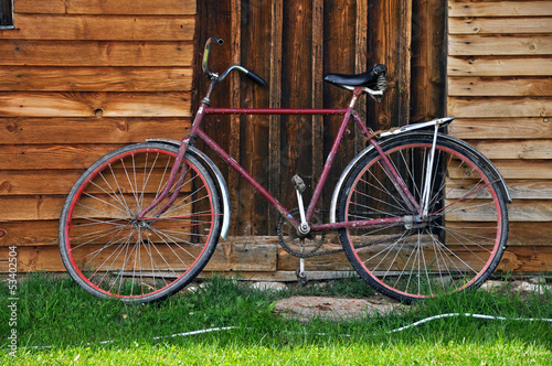 Vintage red bicycle near a wooden house