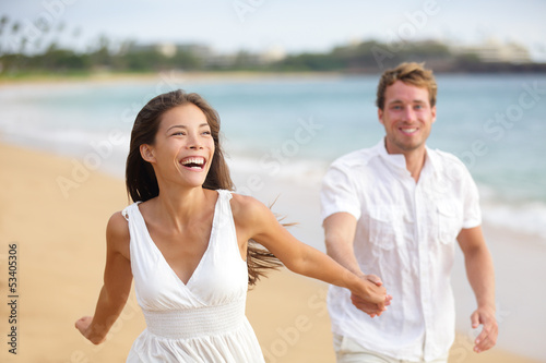 Beach couple running having fun laughing together