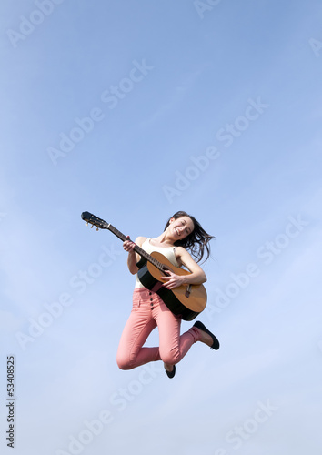 Frau springt mit Gitarre