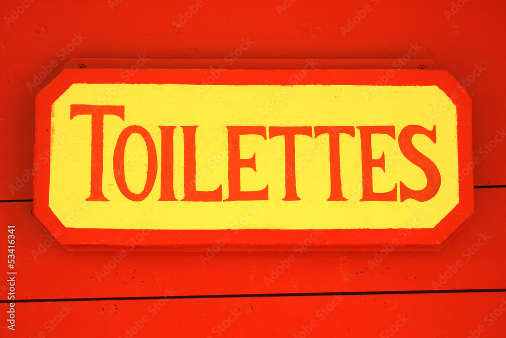 Ancient toilet sign on red wooden background