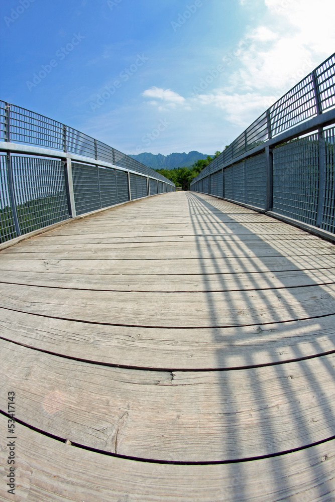 long bridge with a wooden walkway and handrail made of galvanize