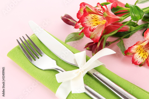 Festive dining table setting with flowers on pink background