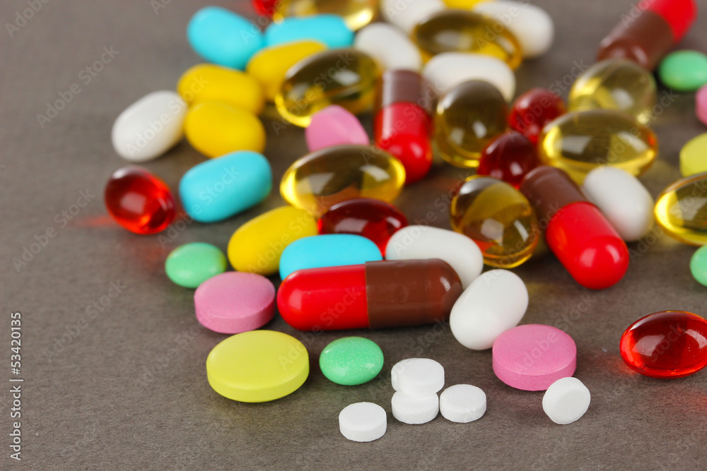 Assortment of pills, tablets and capsules on grey background