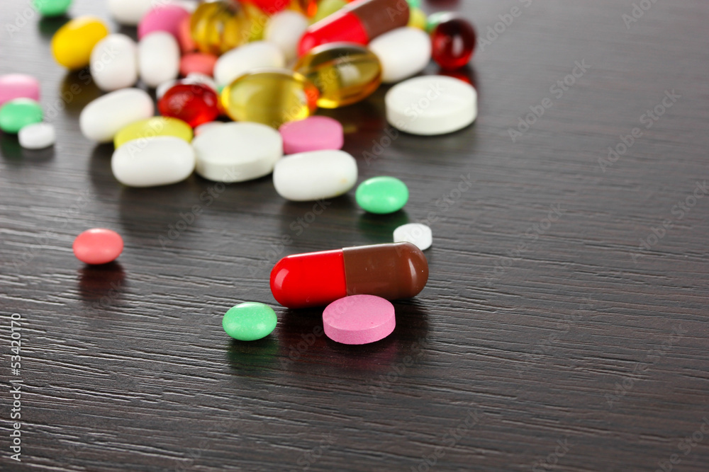 Assortment of pills, tablets and capsules on wooden table