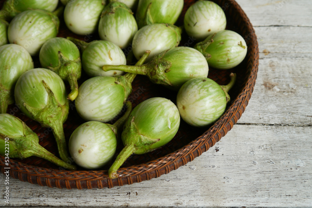 green eggplants in the threshing basket on wooden table
