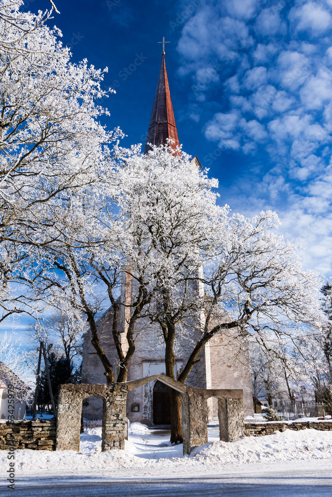 weathered catholic church on a snowy trees