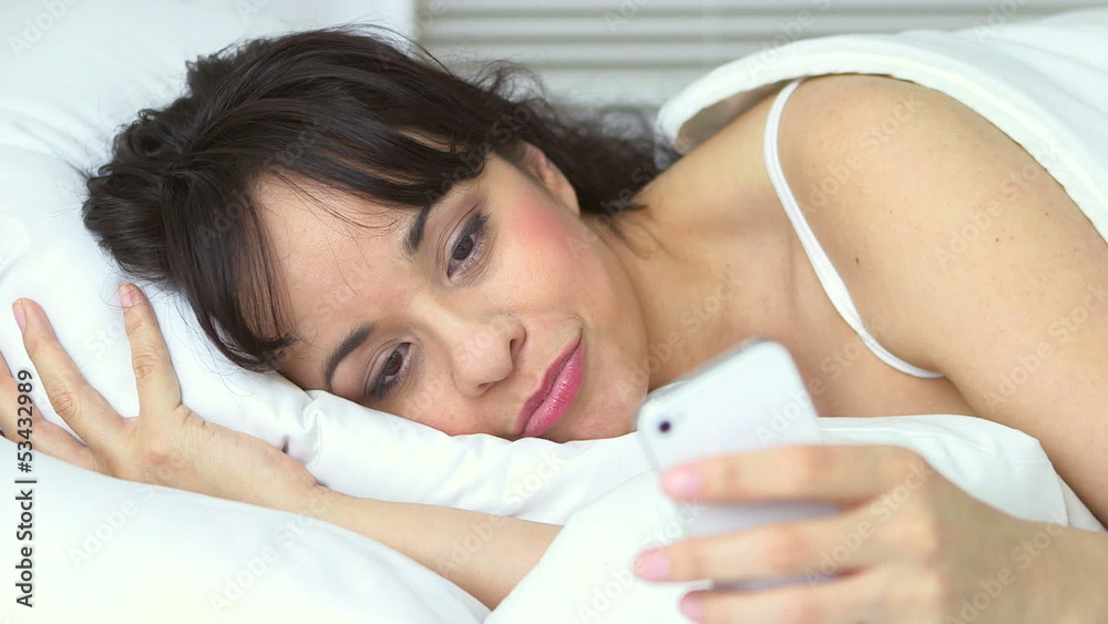 Young woman lying in bed texting Young woman lying in bed texting