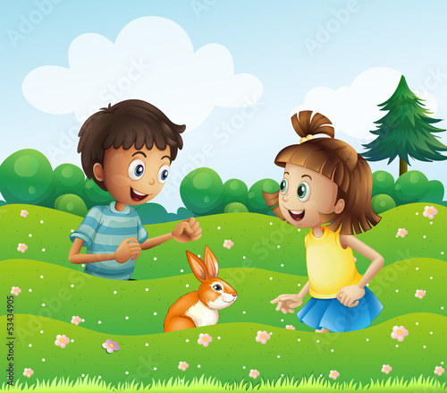 Fototapeta Naklejka Na Ścianę i Meble -  A girl and a boy with a bunny at the hill
