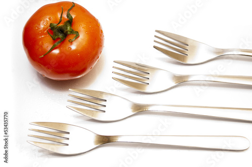 Perspective table forks in a row and a red tomato