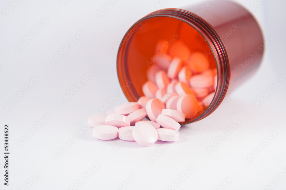 Pink tablet and brown bottle on white Pink tablet and brown bottle on white