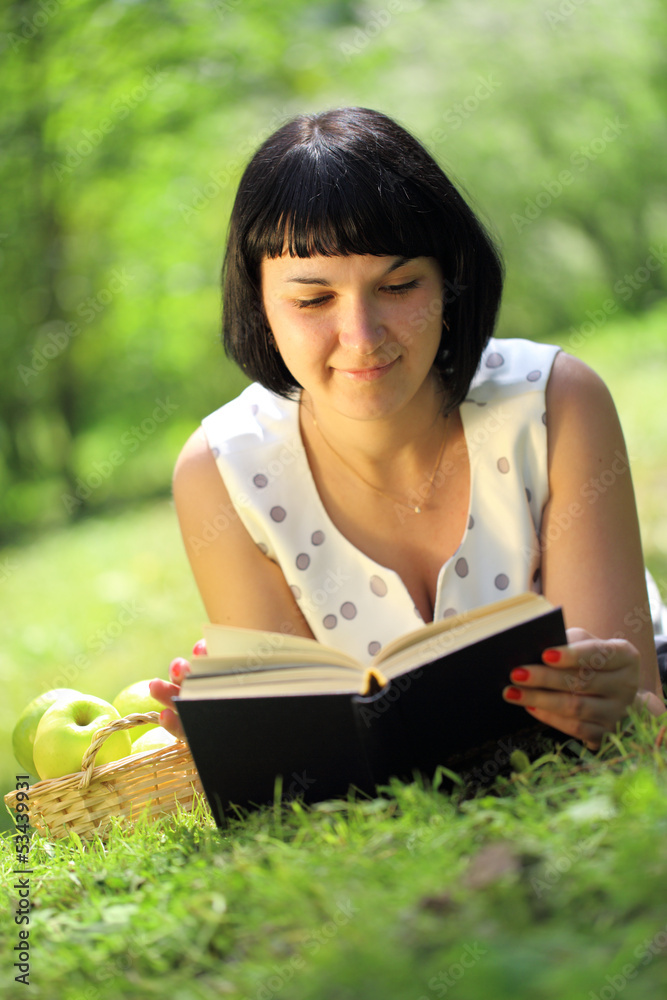 Obraz premium Young woman reading book on grass