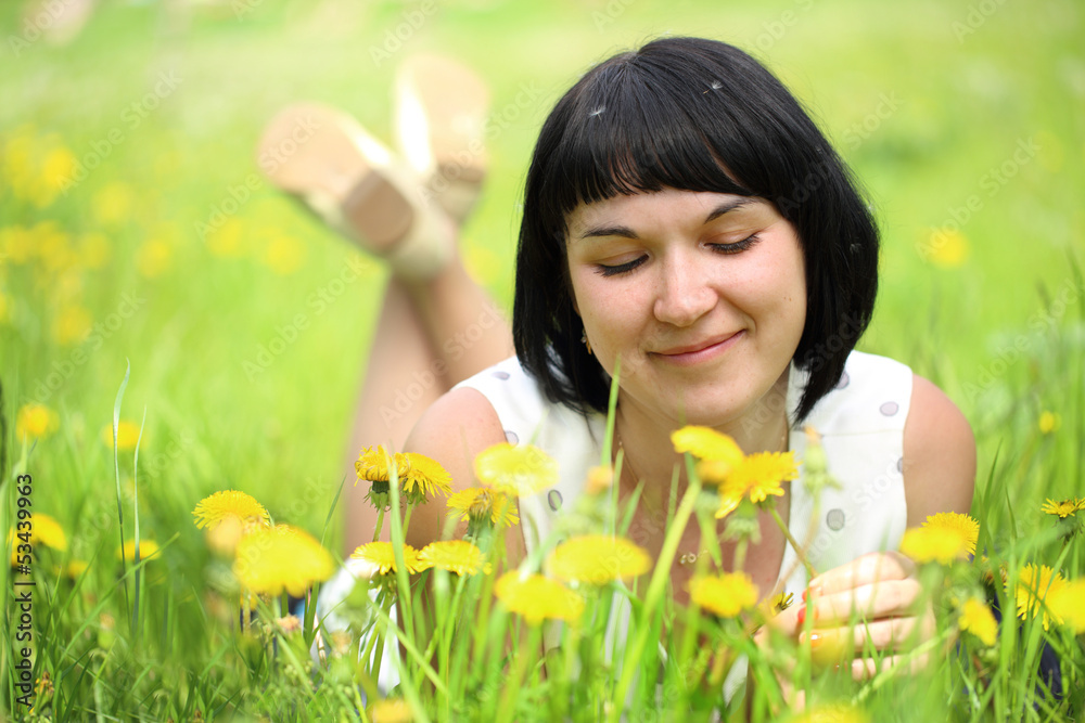 Young woman lying on grass in the field of dandelion Young woman lying on grass in the field of dandelion