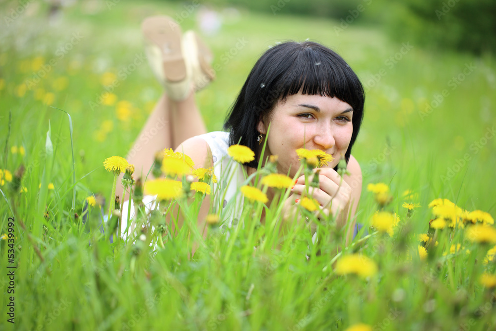 Young woman lying on grass in the field of dandelion Young woman lying on grass in the field of dandelion