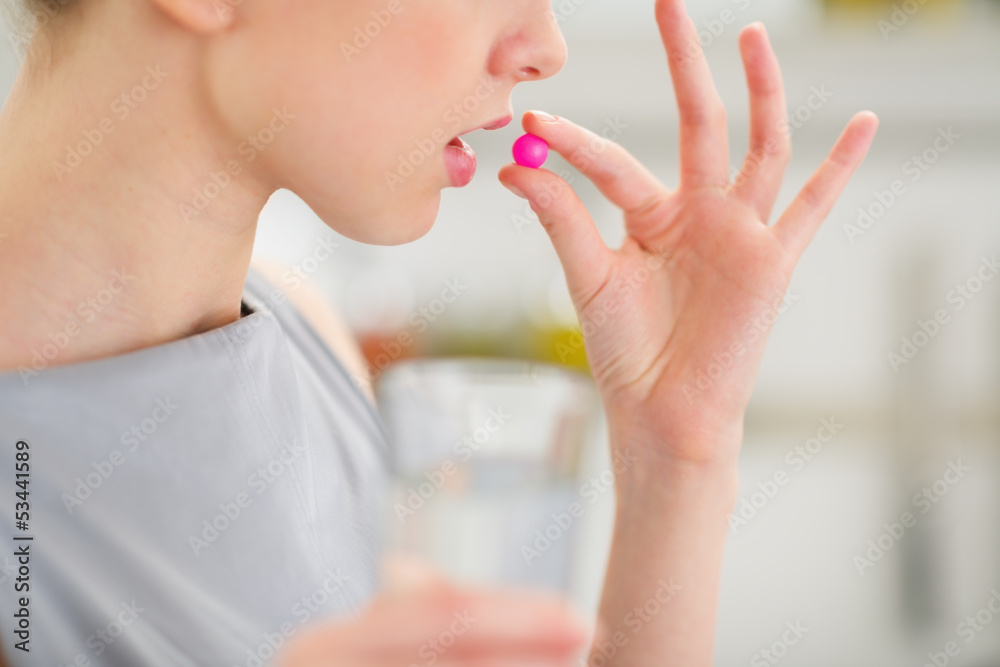 Closeup on young housewife eating pill Closeup on young housewife eating pill