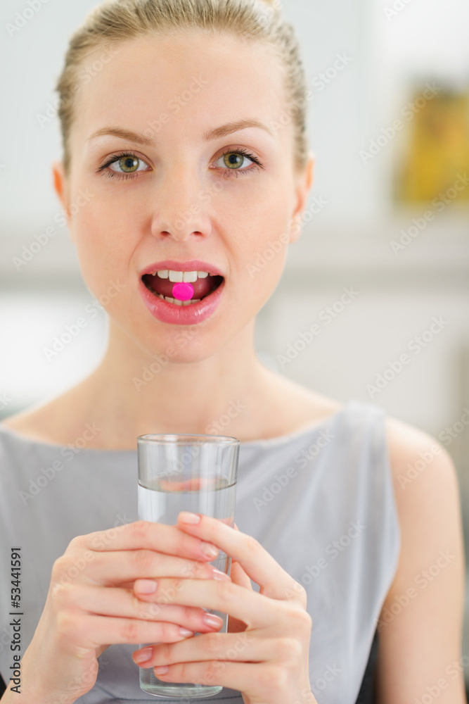 Young woman with pill in mouth - obrazy, fototapety, plakaty 