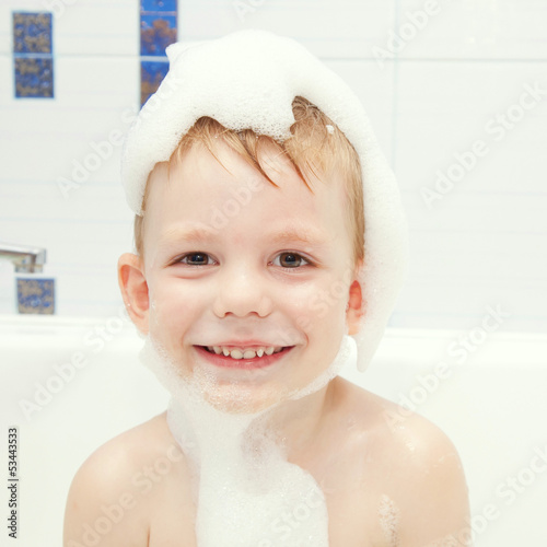 Little child in a cap of foam soap smiling