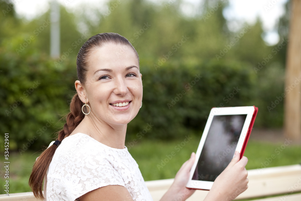 Fototapeta premium Young woman using a tablet computer on a park
