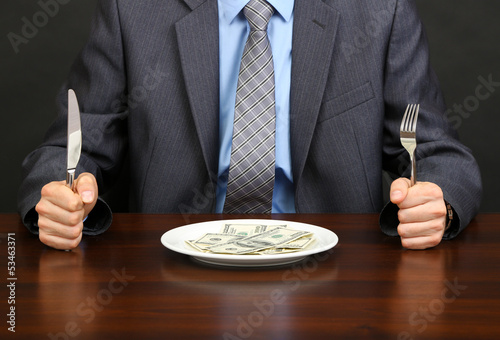 Принти на полотні Young businessman having dinner dollars on black background