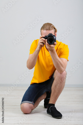 Handsome photographer with camera,on gray background © Africa Studio