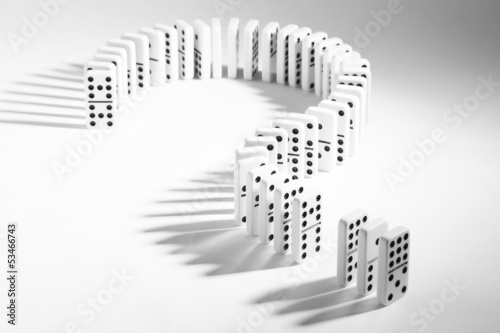 Dominoes in shape of question mark on plain background