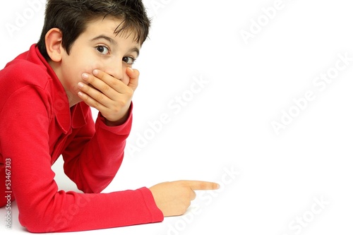 Young boy with hand over his mouth pointing to something photo