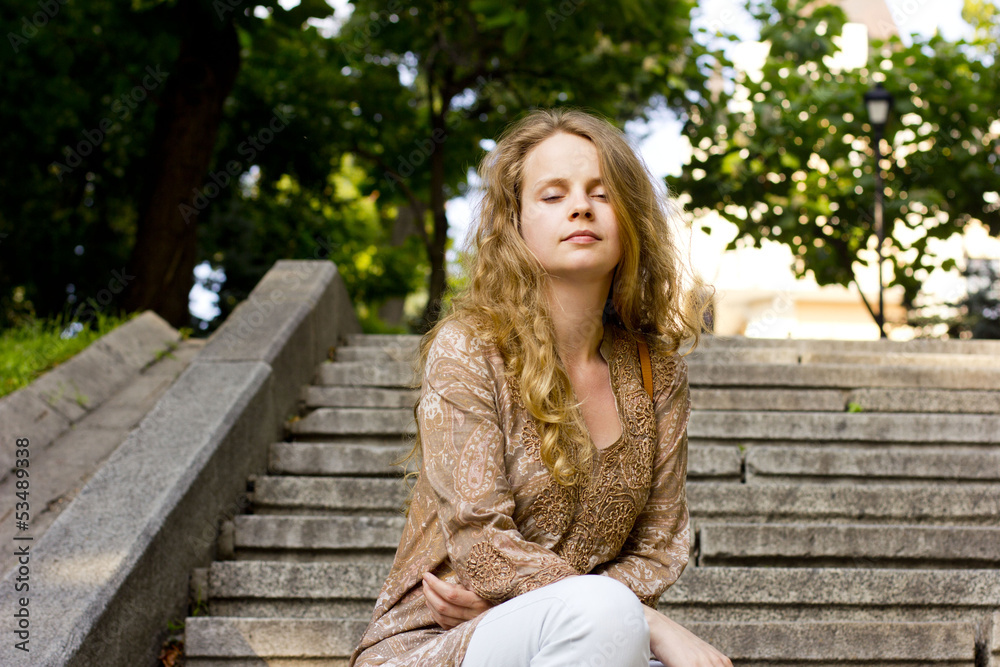 beautiful blonde woman relaxes on the steps in the park beautiful blonde woman relaxes on the steps in the park