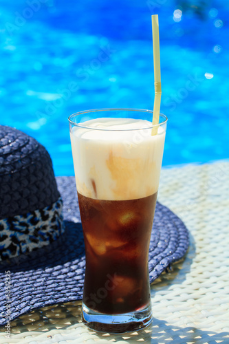 Ice coffee Fredo against blue clear water of the swimming pool photo