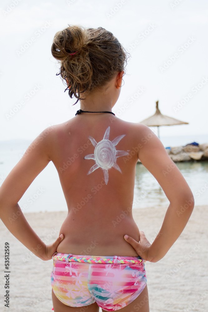 Sun protection - young girl with sunblocker on the beach - obrazy, fototapety, plakaty 