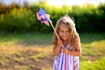 Happy adorable little girl smiling and waving American flag outs