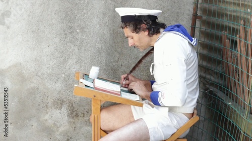 man in middy blouse writing with a feather photo