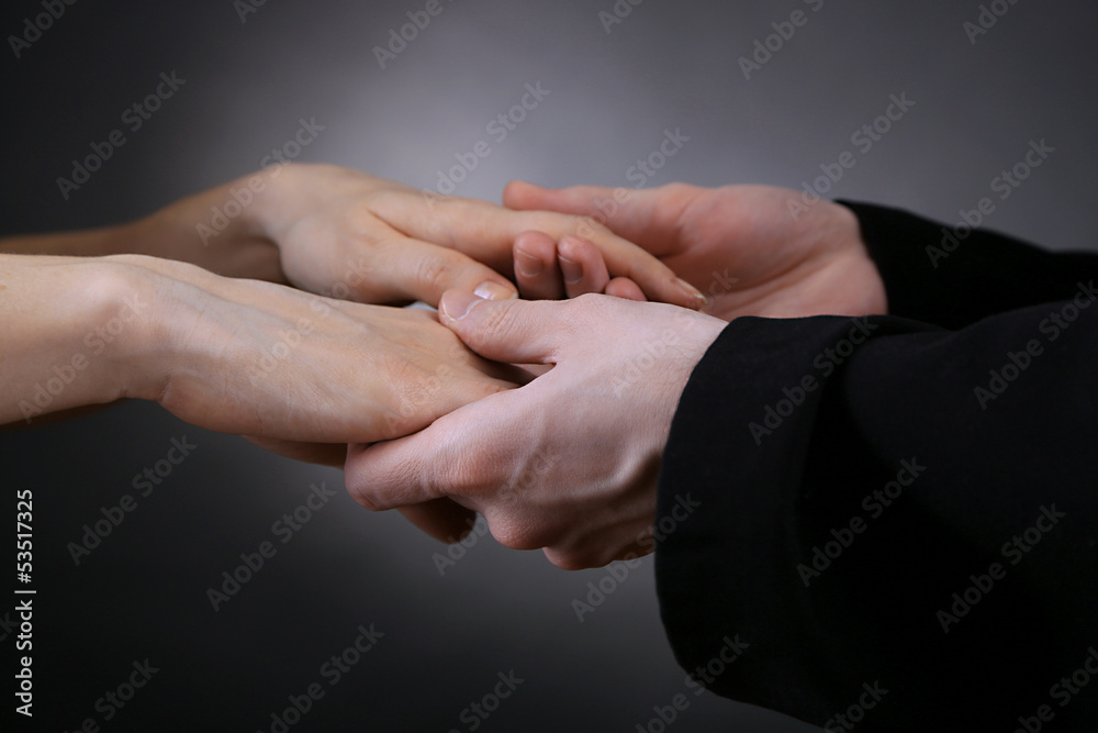 Priest holding woman hands, on black background