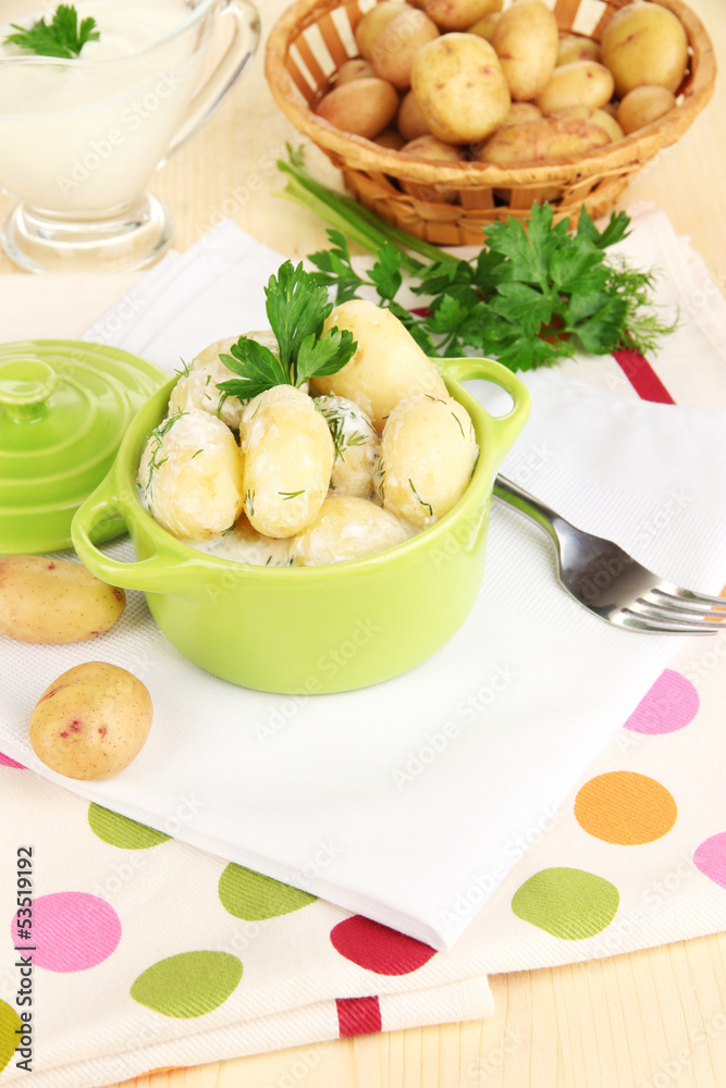 Tender young potatoes with sour cream and herbs in pan