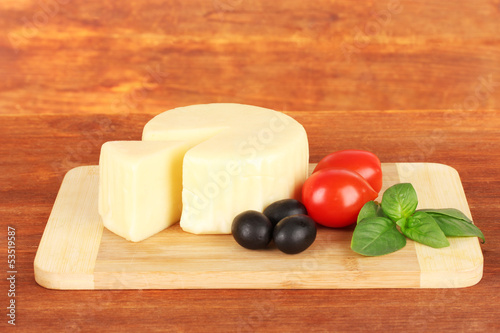 Cheese mozzarella,basil and vegetables on wooden background