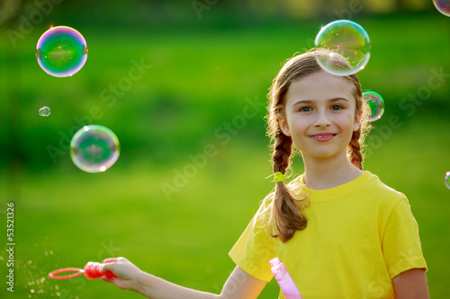 Summer joy - lovely girl blowing soap bubbles