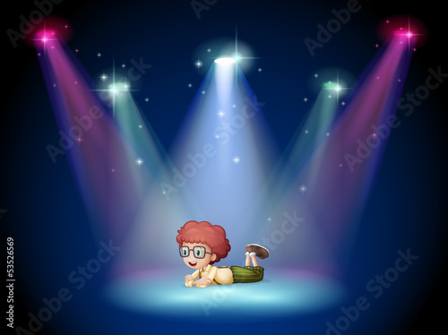 A boy lying in the middle of the stage with spotlights