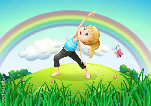 A girl stretching at the top of the hill with a rainbow