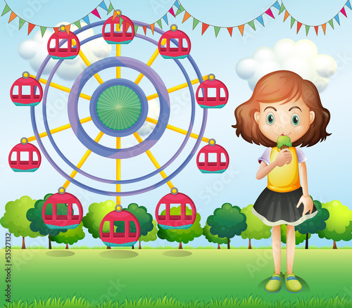 A girl eating an ice cream near the ferris wheel