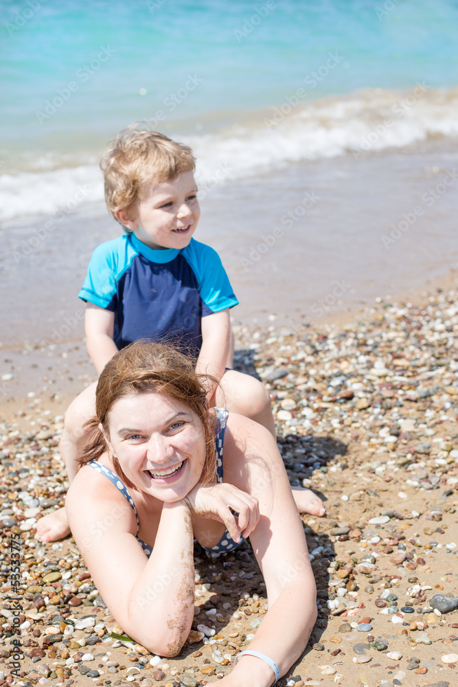 Young mother and little son having fun on beach