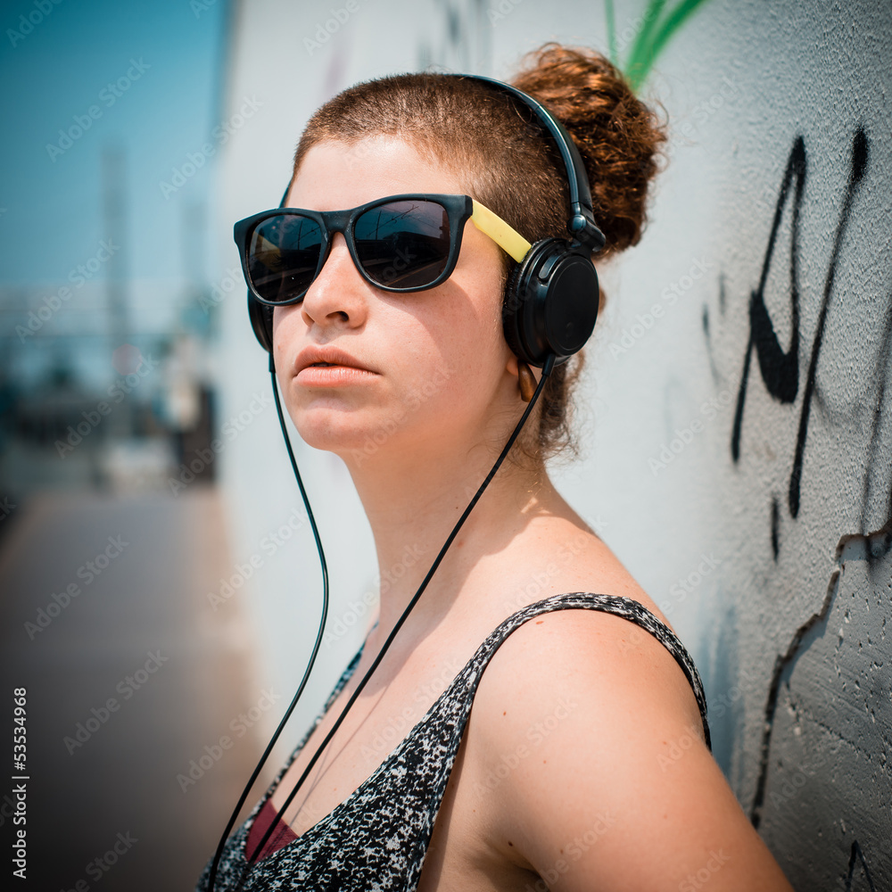 Naklejka premium beautiful stylish modern young woman listening to music