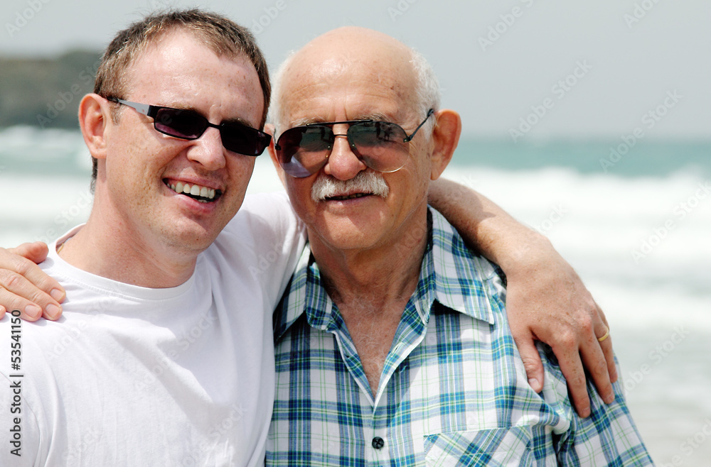 adult son and father walking together on the beach adult son and father walking together on the beach