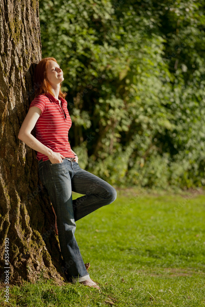 A woman relaxing next to a tree A woman relaxing next to a tree