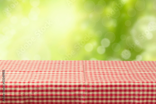 Empty table coved with tablecloth over bokeh garden