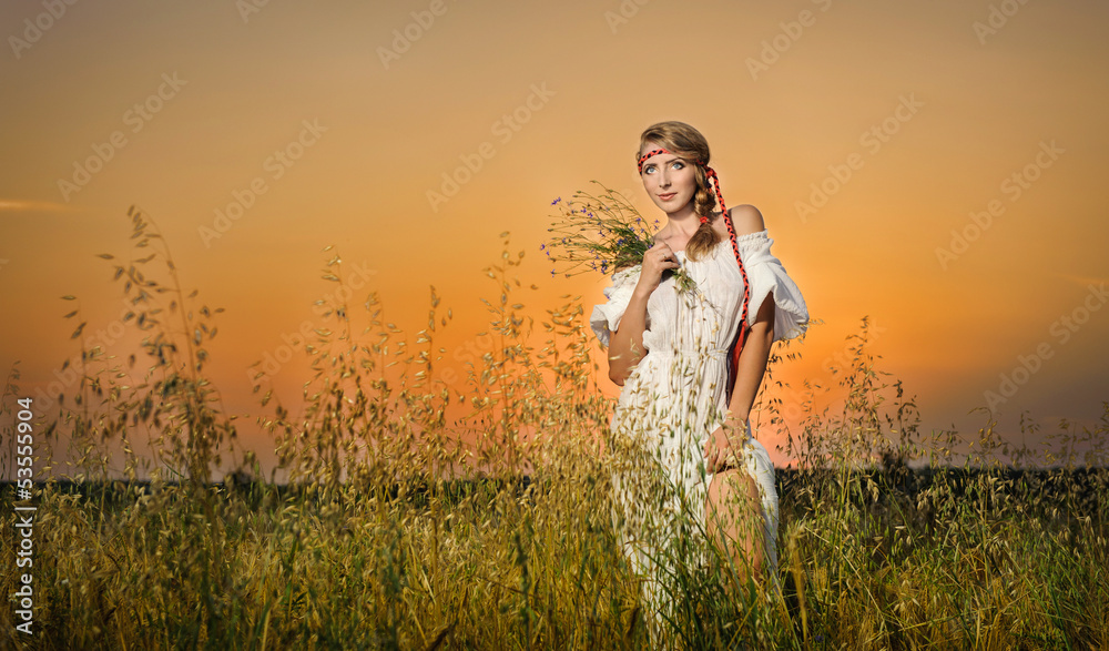  Woman standing on a wheat field with sunrise on the background