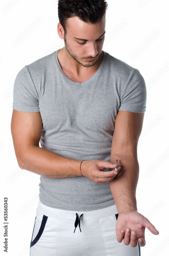 Athletic young man injecting medicine in his arm with syringe Athletic young man injecting medicine in his arm with syringe