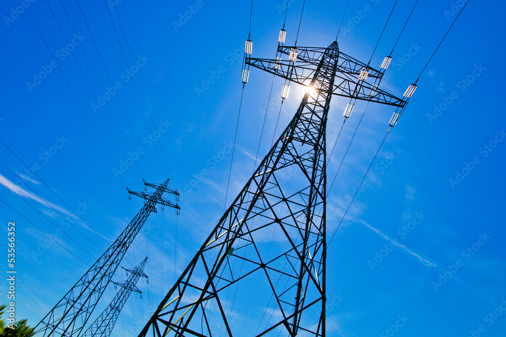 Strommast mit Sonne vor blauem Himmel Strommast mit Sonne vor blauem Himmel