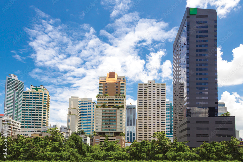 Cityscape behind a public park with blue sky background.