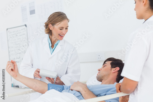 Smiling doctor measuring blood pressure of a patient